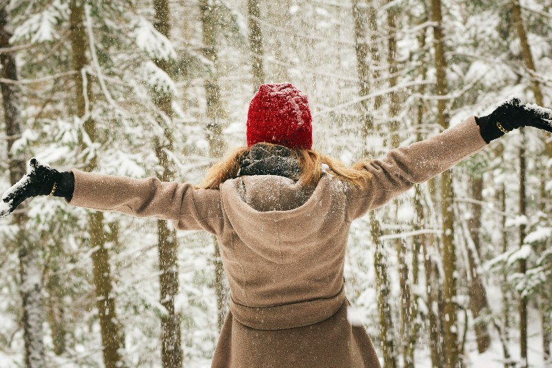 Donna in mezzo alla neve che accoglie la natura 